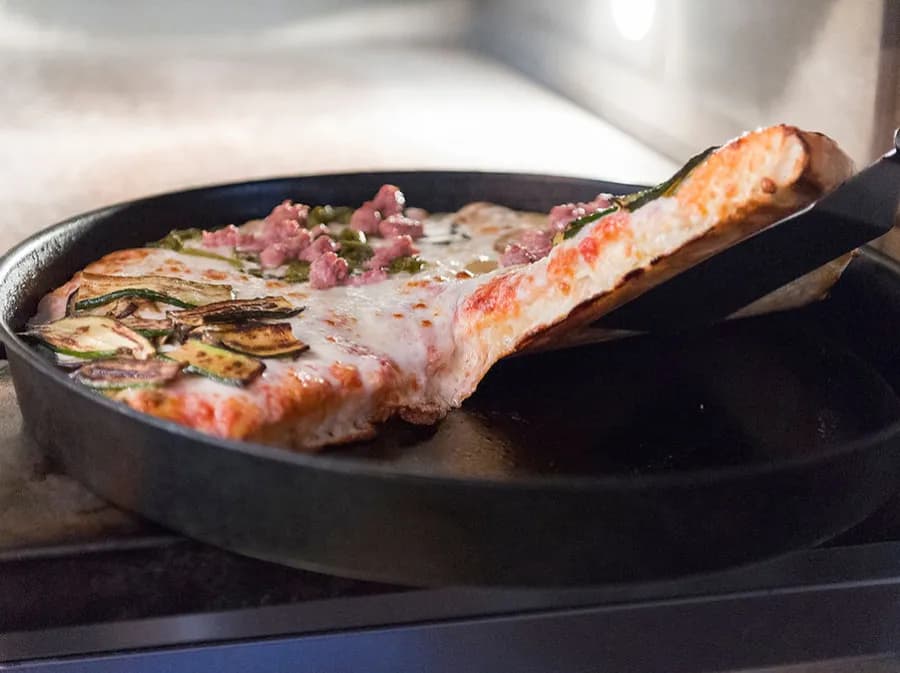 Pizza al trancio appena sfornata con ingredienti freschi